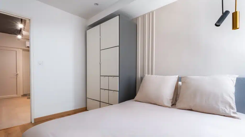 Chambre claire, suspensions noire et laiton au-dessus du lit, tête de lit à moulures verticales