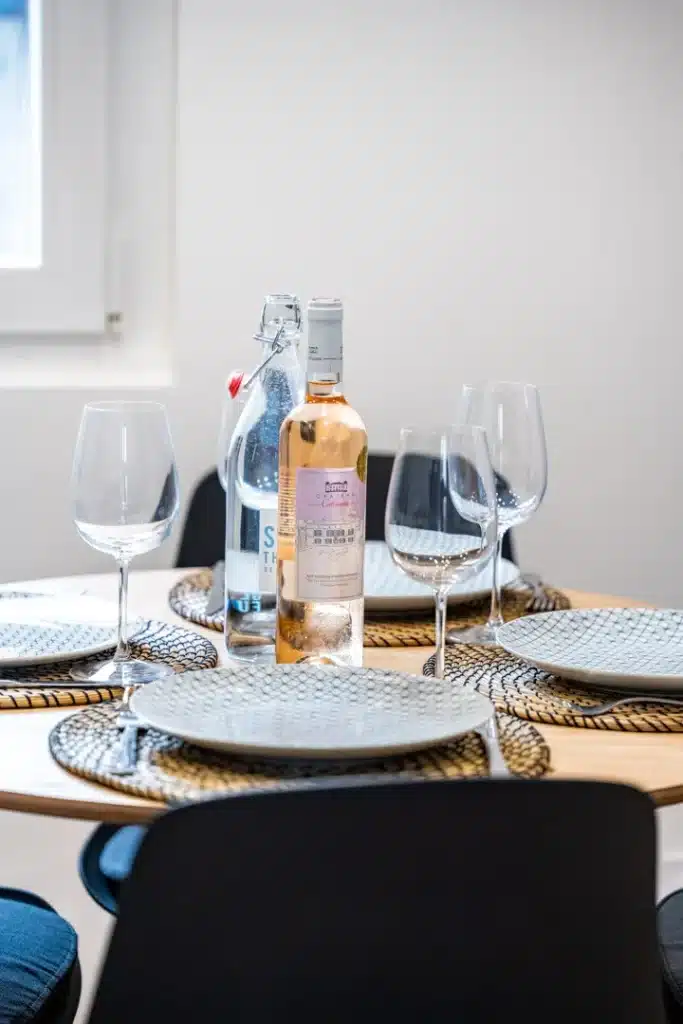 Table ronde dressée, assiettes, verres à pied et carafe